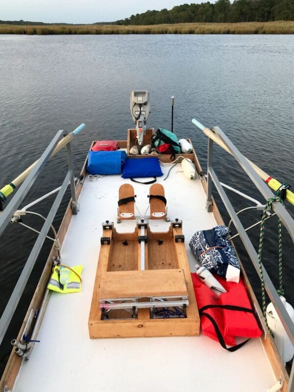 A boat with two oars and several bags on the deck.