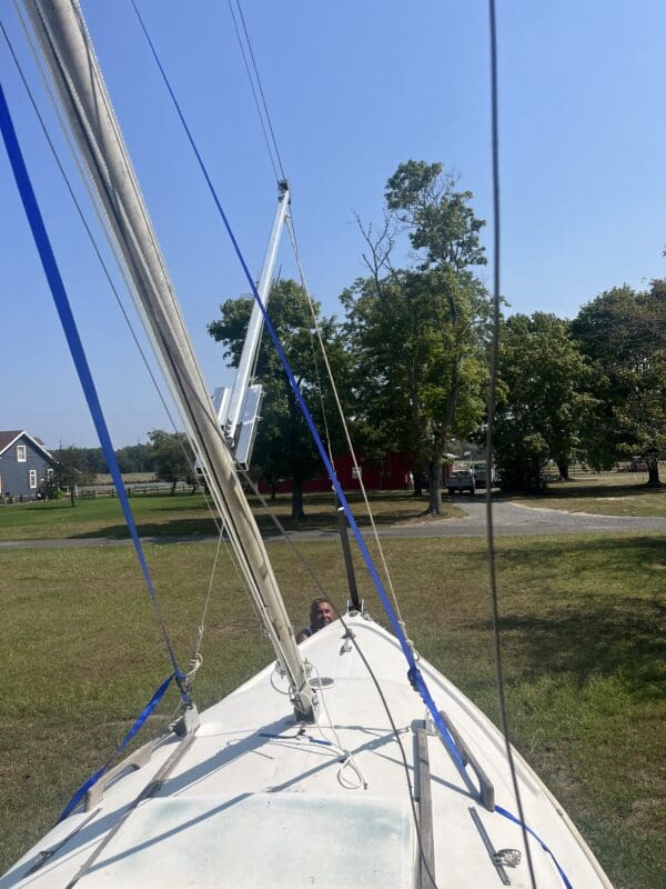 A sailboat is sitting in the grass near some trees.