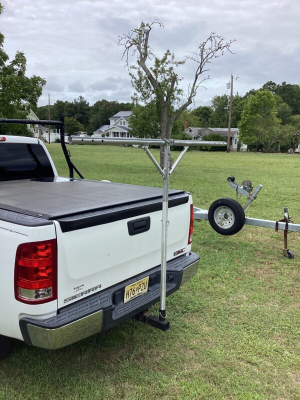 A white truck parked in the grass near a tree.