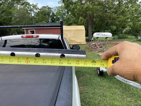 A person holding a tape measure in front of a truck.