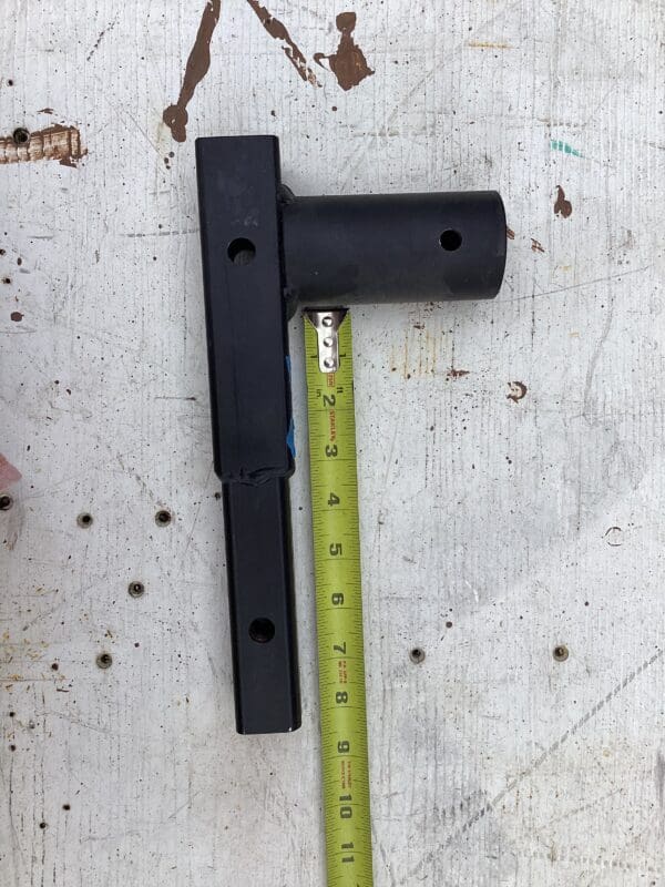 A black metal hinge with a yellow ruler next to it.